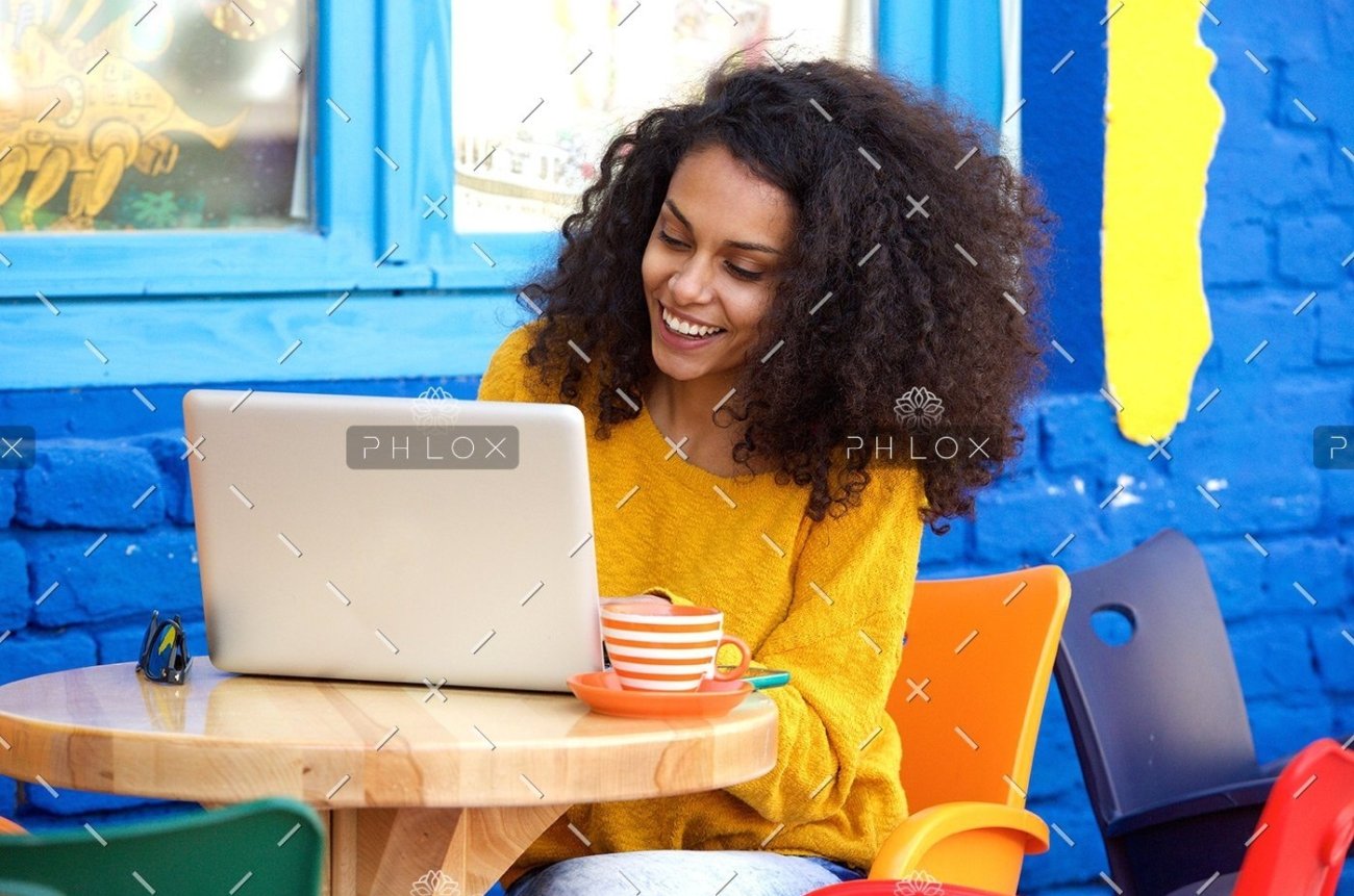 demo-attachment-29-happy-young-woman-sitting-at-outdoor-cafe-using-PFFBJ93